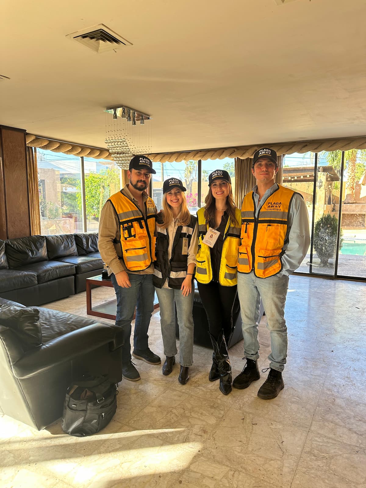 Los cuatro integrantes del equipo de Plagaway, con gorra y chaleco de la marca, de pie en la sala de una casa que atendieron